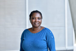 Elizabeth Olanloye wearing a blue top and smiling at camera for portrait image