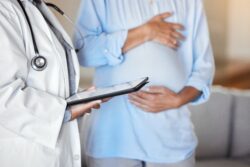 Zoomed in image of woman holding bump standing next to doctor in white coat