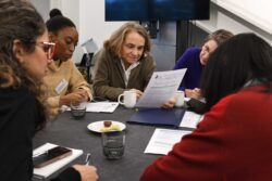 Workshop attendees at a round table looking at a piece of paper.